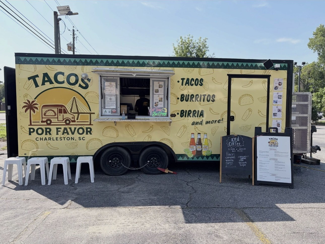 The yellow Tacos Por Favor truck with its service window, chalkboard and menu stand