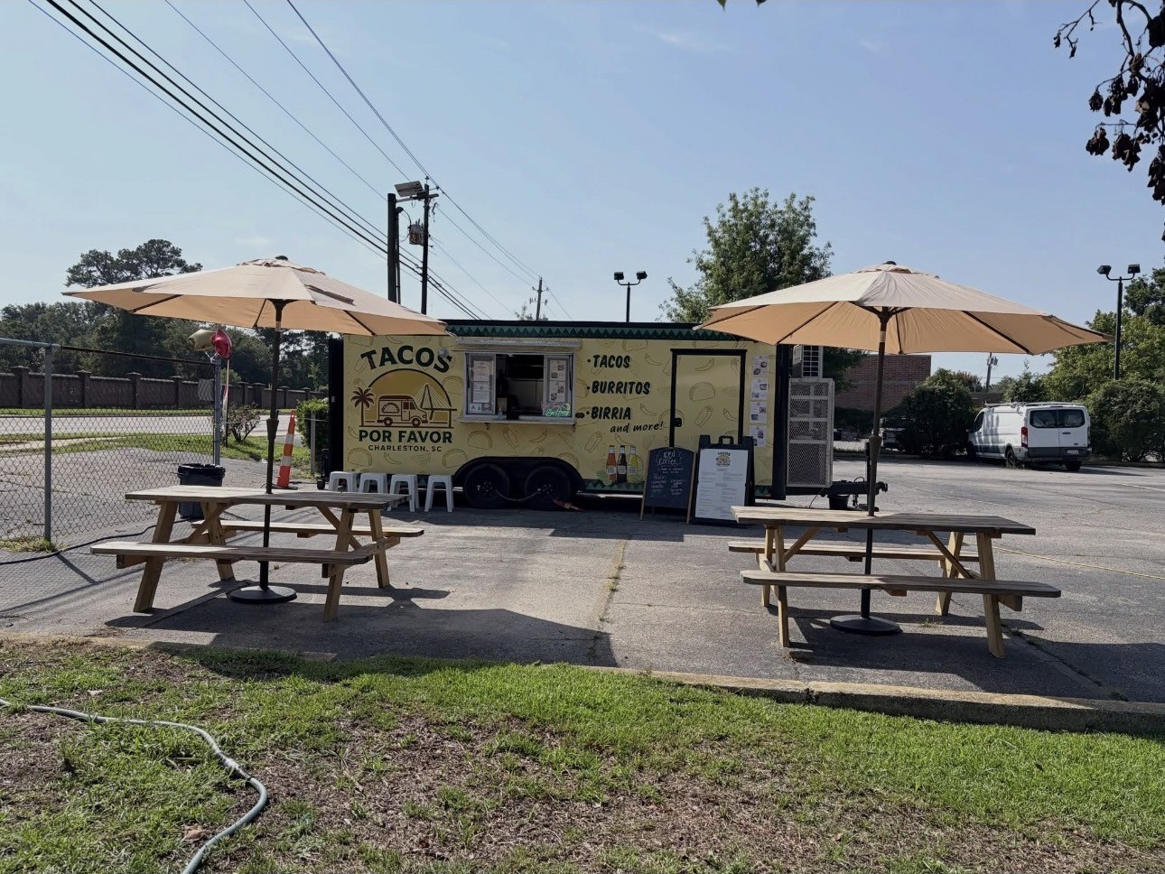 Picnic tables under umbrellas beside the Tacos Por Favor truck
