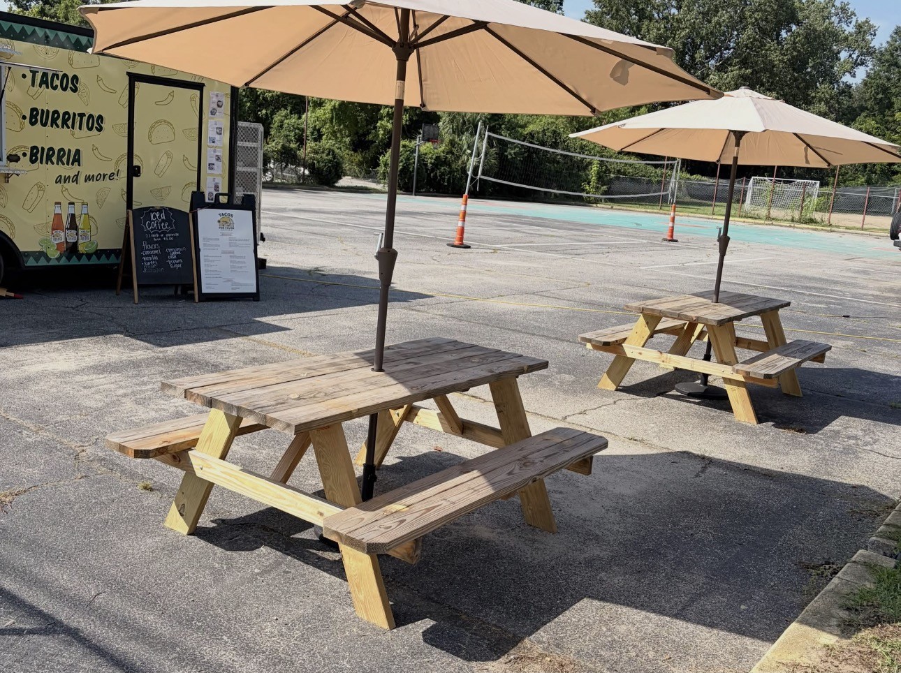 A wooden picnic table with an umbrella and the truck behind it